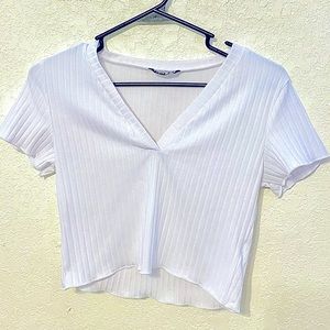 A small white crop top with a v cut, made of cotton and polyester